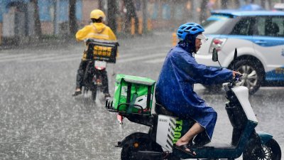 8月10日，深圳遭遇暴雨，快递小哥冒雨行进在送货途中。（图取自中新社）