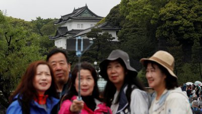 图为2019年，有中国游客在日本东京皇居前拍照留念。（路透社档案照）