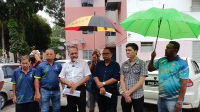 佳日星（左3）在槟岛市政厅官员及乡委会成员的陪同下，冒雨撑伞宣布为大英义学园3组屋增15架闭路电视。