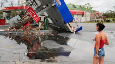美国佛罗里达州8月底遭“伊达利娅”飓风袭击，一个油站在风暴中被吹倒。（图取自路透社）