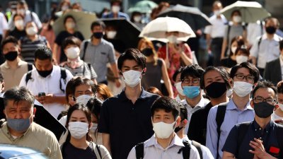 新冠肺炎疫情期间，日本东京街头的人们都戴上口罩防疫。（图取自路透社）