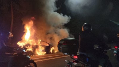 一辆汽车在路上被大火吞噬，浓烟四起，一人受轻伤。（图取自《8视界新闻网》）