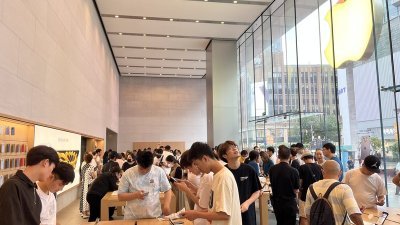 中国消费者在上海市南京东路苹果零售店内试用手机。（图取自中央社）