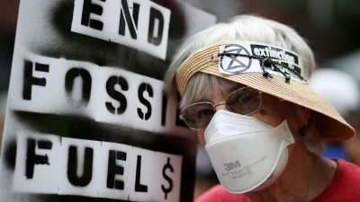 一名环保人士当地时间周日在美国纽约，举著写有“终结化石燃料”的标语参加集会。（图取自法新社）