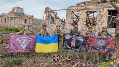 乌克兰当地时间周日宣布，已收复主要前线城巿巴赫穆特南翼的克利斯奇夫卡村，乌克兰军队站在废墟上举著旗帜发表讲话。（图取自乌克兰陆军总司令西尔斯基/路透社）