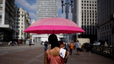 巴西遭到热浪袭击，在该国最大城圣保罗市中心，路人在烈日下撑伞遮挡炙热阳光。（图取自路透社）