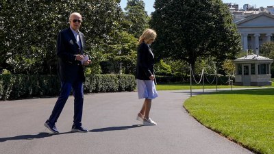 穿著运动鞋的美国总统拜登，和第一夫人吉尔走过白宫的南草坪。（图取自路透社）