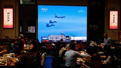 中国首都北京市一家餐厅的大萤幕，播放解放军在台海周边演习的新闻片段。（路透社档案照）