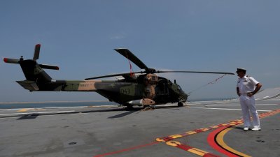 图为2019年，澳洲海军LHD舰“堪培拉”号抵达斯里兰卡科伦坡港后，一名澳洲海军军官站在一架“太攀蛇”直升机旁。（路透社档案照）