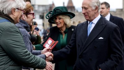 英国国王查尔斯和王后卡米拉在礼拜仪式后，和外头人群中的一些支持者握手，进行短暂交谈。（图取自法新社）