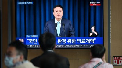 在韩国首尔一火车站，电视屏幕上直播总统尹锡悦就医生反对医疗改革发起罢工的讲话。（图取自法新社）