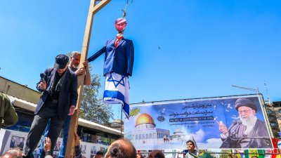 在以色列对叙利亚袭击中丧生的7名伊朗革命卫队成员，周五在伊朗首都德黑兰举行丧礼，示威者吊起贴上以色列总理内塔尼亚胡肖像的假人，以示抗议。（图取自法新社）