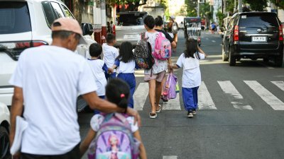 家长们周五在菲律宾首都马尼拉，带放学的孩子回家。（图取自法新社）