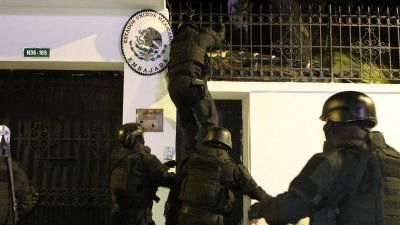 厄瓜多尔警察特种部队于上周五晚闯入墨西哥驻基多大使馆，逮捕寻求庇护的厄瓜多尔前副总统格拉斯。照片显示，一名特种部队人员在其他人员帮助下爬上大使馆围墙。（图取自API/法新社）