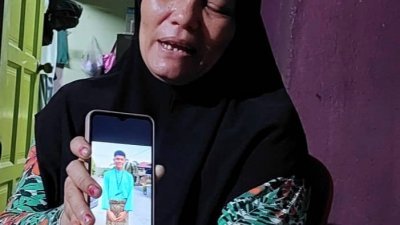 阿斯丽娜难过地出示儿子生前的照片。（图片取自Malaysia Gazett）