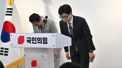 韩国国民力量在周三的国会选举中遭遇惨败，担任党临时领导人指挥竞选的韩东勋（右），周四在位于首尔的国民力量总部召开记者会时鞠躬。（图取自法新社）