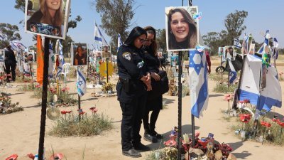 4月7日在以色列南部雷姆集体农庄附近的音乐节现场，以色列士兵参观了一座纪念碑，纪念碑上挂著去年10月7日超新星音乐节哈马斯袭击中被俘或被杀的人的肖像。（图取自法新社）