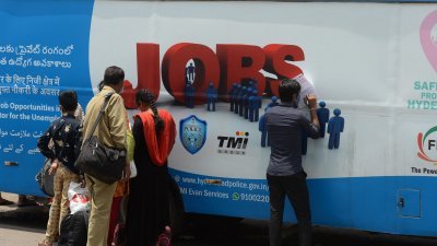 印度泰伦加纳邦海得拉巴市的年轻人，在一辆“就业货车”外填写表格，申请私人领域的工作。（法新社档案照）