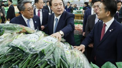 韩国总统尹锡悦（中）3月18日在首尔视察Hanaro Mart的分店，期间查看了葱的价格。（图取自法新社）
