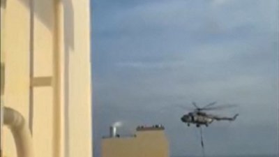 图为周六社交媒体上UGC视频的截图，显示在霍尔木兹海峡附近，伊朗革命卫队人员从直升机快速降落到“白羊座”号集装箱船上。（图取自法新社/匿名）