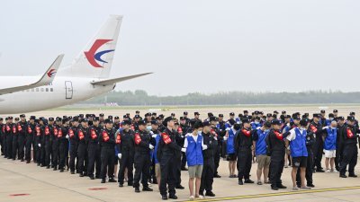 在柬埔寨涉赌诈违法遭押解回国的130名中国人，周六早上抵达湖北省武汉市的天河国际机场，在停机坪列队。（图取自中新社）