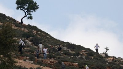 武装的以色列人周六在以色列占领下的约旦河西岸附近的一座小山，寻找一名失踪的以色列少年。（图取自法新社）