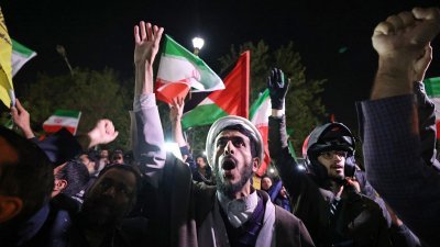 伊朗对以色列发动无人机和导弹袭击后，民众周日聚集在英国驻德黑兰大使馆前，挥舞著伊朗国旗和巴勒斯坦旗。（图取自法新社）