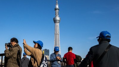 一群旅客在日本首都东京的隅田公园，欣赏当地地标晴空塔并拍照。（图取自法新社）