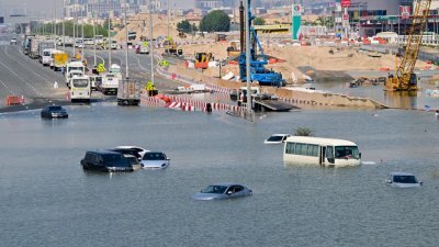 迪拜周三遭遇破纪录大雨，汽车周四仍被困在一条被洪水淹没的街道上。（图取自法新社）
