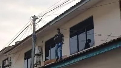 两贼潜入屋内偷窃，其中一人站在屋顶时被附近居民发现。(视频截图)