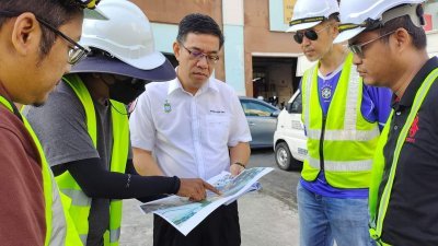 黄汉伟（左3）向承包商员工了解亚依淡衔接敦林苍祐大道公路项目的封路事宜。