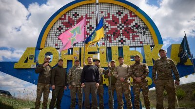 乌克兰官方4月19日发布照片，显示总统泽连斯基（左4）在标志著顿涅茨克地区入口的路标前与乌克兰士兵合照。（图取自乌克兰总统新闻服务/法新社）