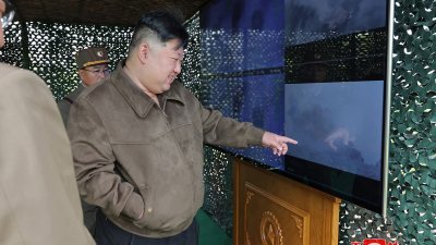 朝鲜最高领导人金正恩（中）周一透过荧幕，观察运用超大型火箭炮的“核反击模拟综合战术训练”。（图取自朝中社/法新社）
