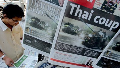 泰国军方2006年9月19日发动政变，推翻时任首相塔辛震惊全球。图为政变的消息在隔天成为各大报章的封面头条，一名男子在吉隆坡市中心的一家店内阅读相关新闻。（图取自法新社档案照）
