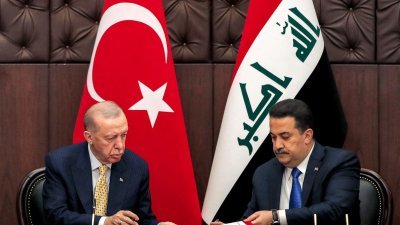 土耳其总统埃尔多安（左）与伊拉克总理苏达尼交换签署的协议。（图取自法新社）