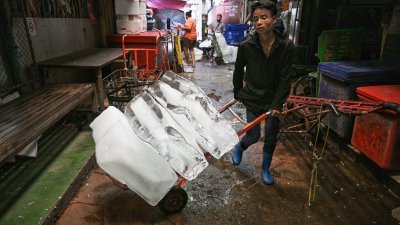 4月通常是泰国一年中最热的时间，最近更遭到热浪袭击。图为一名工人在曼谷的生鲜市场运送冰块。（法新社档案照）