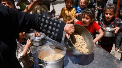 流离失所的巴勒斯坦儿童，在加沙南部的拉法市领取食物。（图取自法新社）