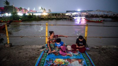 炎热的天气还得面临停电，缅甸仰光市的市民周五晚到码头乘凉。（图取自法新社）