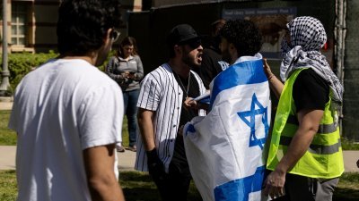 在加州大学洛杉矶分校 (UCLA) 校园内，一名亲以色列示威者（左）与另一名亲巴勒斯坦示威者当地时间周日发生争执。（图取自法新社）