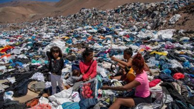 2021年9月在智利阿塔卡马沙漠（以快时尚垃圾场而闻名），数名妇女在大量废弃物品中寻找可用的衣服。（图取自法新社档案照）