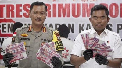 阿迪普（右）展示，所起获的面额一万新元伪钞。左为印尼廖内省警察公共关系主管扎赫纳维。（图取自网络）