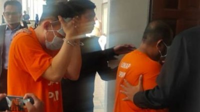 两名嫌犯身穿橘色囚衣，被反贪会官员押送入法庭。