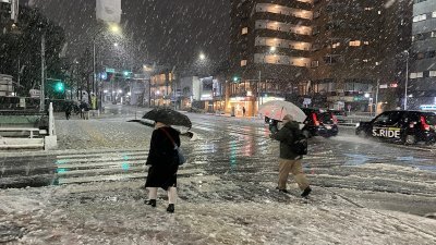 日本东京周一下午开始降下大雪，路上随处可见积雪、雪泥和冰块，行走时必须特别留心。（图取自中央社）