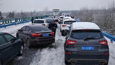 大批车子堵在了湖北省的高速公路上，受困民众下车走动。（图取自网络）