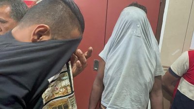 2名被告被押往槟城推事庭面控时，用衣服遮住脸部，不让其样貌曝光。