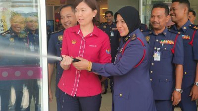 黄诗情（左起）和莎雅妮检查消防喉辘，确保运作正常，在紧急的关键时刻可以派上用场。