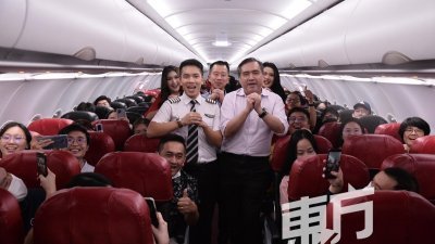陆兆福（右）与亚航机组人员一同祝福乘客农历新年快乐。