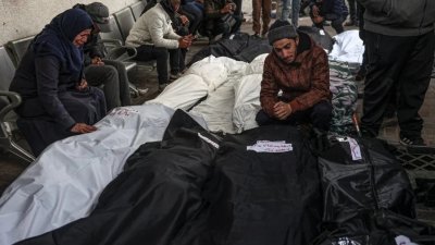 以色列连夜轰炸加沙地带南部的拉法，巴勒斯坦人在医院辨认罹难的亲人后，难过地看著用尸袋包裹的遗体。（档案照，图取自法新社）