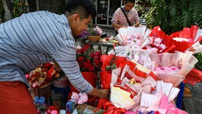 周三是情人节，柬埔寨首都金边的商贩摆好待出售的鲜花，吸引民众购买。（图取自路透社）