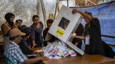 印尼总统和议会周三的选举结束投票后，一名选举官员在万丹省勒巴克县凯内克斯村的投票站，清空投票箱进行计票。（图取自法新社）